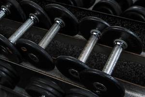 Different black dumbbells in the modern gym photo