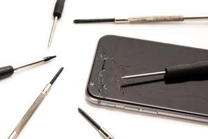 Broken smartphone and small screwdrivers for repair photo