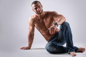 Handsome muscular man wearing jeans posing in studio photo