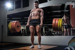 Strong man doing deadlift exercise in the gym photo