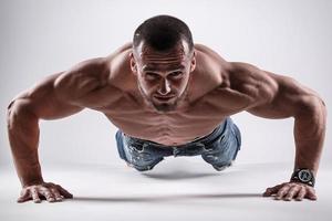 Handsome man doing push up exercise against gray background photo