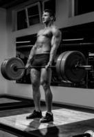 hombre fuerte haciendo ejercicio de peso muerto en el gimnasio foto