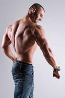 Handsome muscular man wearing jeans posing in studio photo
