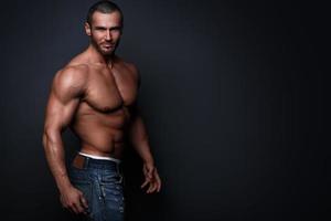 Handsome muscular man wearing jeans posing in studio photo