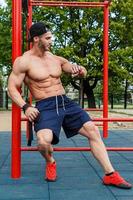 Man is looking on his wrist watches, while resting during workout photo