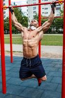 Muscular man doing pull-ups on horizontal bar photo