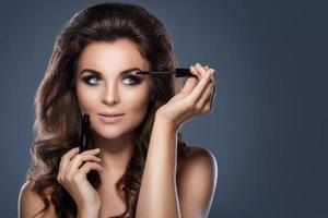 Beautiful woman applying mascara on her lashes photo
