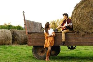 pareja joven en el pueblo. chico está tocando la guitarra para su novia. foto