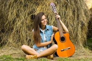 mujer joven y feliz tocando la guitarra en el pueblo foto