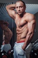 joven musculoso posando en el gimnasio foto