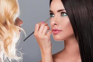 Makeup artist applying eyeshadow on model eyes photo