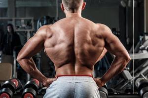 Young man showing his muscular back in gym photo