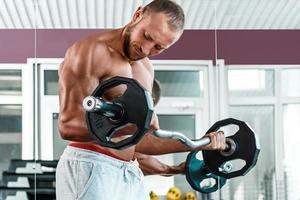 Muscular man during workout in the gym photo