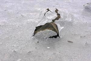 roca que se agrieta a través del hielo en vagspollen en las islas lofoten, noruega en el invierno. foto