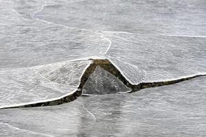 roca que se agrieta a través del hielo en vagspollen en las islas lofoten, noruega en el invierno. foto