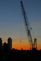 Construction against a background of a silhouette of New York City at sunset. photo