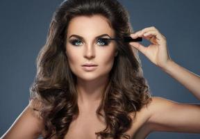 Beautiful woman applying mascara on her lashes photo