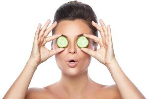 Beautiful woman with cucumber slices on white background photo