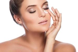 Young and beautiful woman applying moisturizing cream on her face photo