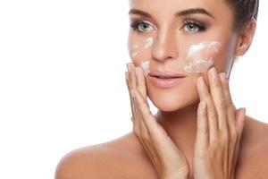 Young and beautiful woman applying moisturizing cream on her face photo