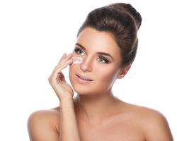 Young and beautiful woman applying moisturizing cream on her face photo
