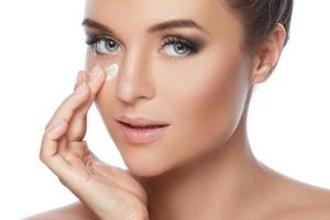 Young and beautiful woman applying moisturizing cream on her face photo