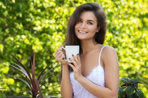 Happy woman drinking coffee on the balcony or in the garden photo