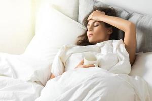 Sick woman under blanket with a cup of hot drink photo