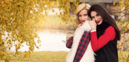 Portrait of two beautiful girls friends in autumn park photo