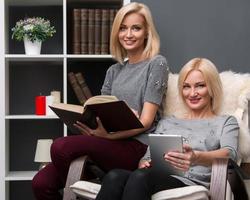 Mother and adult daughter reading at home photo