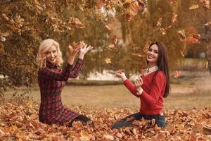 Two beautiful girls friends having fun in autumn park photo