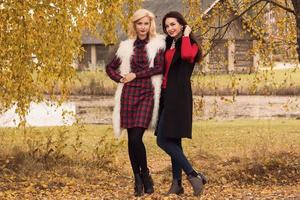 Portrait of two beautiful girls friends in autumn park photo