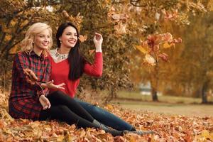 Two beautiful girls friends having fun in autumn park photo