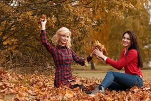 Two beautiful girls friends having fun in autumn park photo