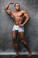 Sexy and muscular man posing against concrete wall photo