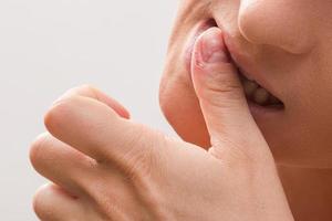 Closeup of a female mouth biting her fingers photo