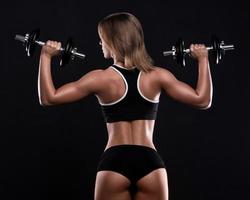 Young and beautiful fitness girl with dumbbells photo