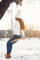 Happy girl on rope swing at sunny winter day photo