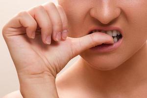 Closeup of a female mouth biting her fingers photo