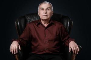 Portrait of serious senior man in armchair photo