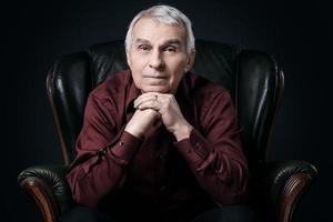 Portrait of serious senior man in armchair photo