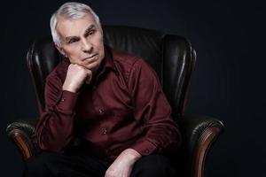 Portrait of serious senior man in armchair photo