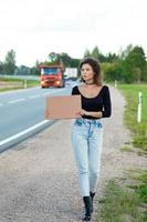 Hitchhiker on the road is holding a blank cardboard sign photo