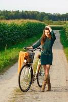 Woman is cycling by the country road in the cornfield photo