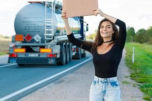 Hitchhiker on the road is holding a blank cardboard sign photo