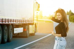 Hitchhiker on the road is holding a blank cardboard sign photo