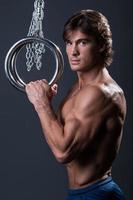 Strong muscular young gymnast guy and rings photo