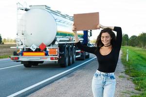 Hitchhiker on the road is holding a blank cardboard sign photo