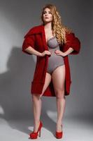 Plus size model wearing lingerie and red knitted coat photo