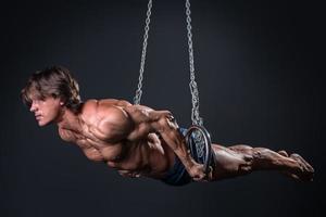 Strong and muscular gymnast guy on the rings photo